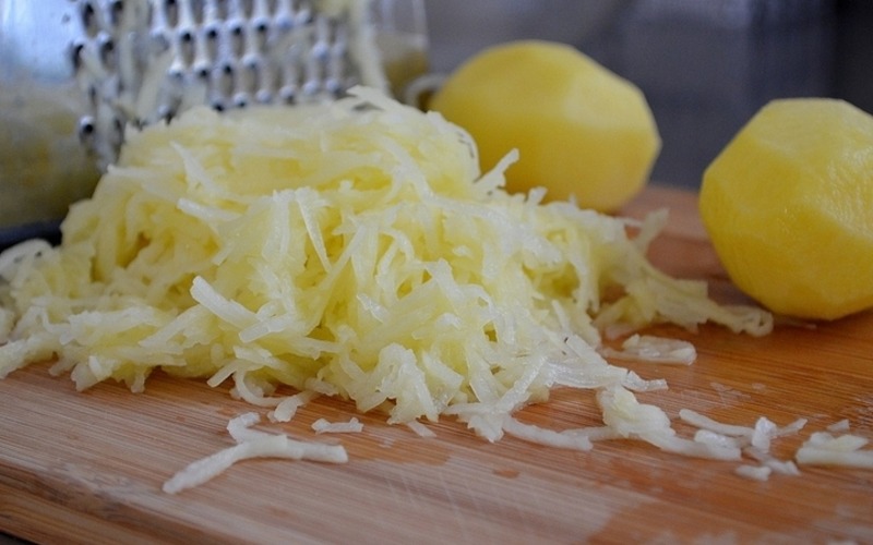 Картофель моем, чистим и трем на средней терке. По желанию картофельный фарш модно отжать от сока, промыть от лишнего крахмала, тогда драники получатся белоснежными. Но лучше этого не делать, тогда драники будут более вкусными, хрустящими и румяными.