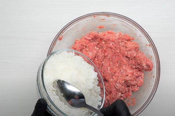 Далее добавляем в фарш рис, снова хорошенько перемешиваем. Вбиваем в миску с фаршем яйцо, солим и перчим. В очередной раз перемешиваем, чтобы получилась однородная масса.