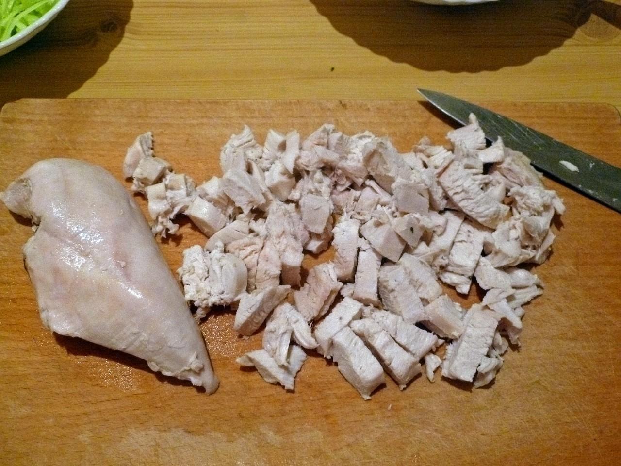 Когда курица почти сварилась, достаем ее из бульона, даем немного остыть, отделяем мясо от кости и режем кубикам 