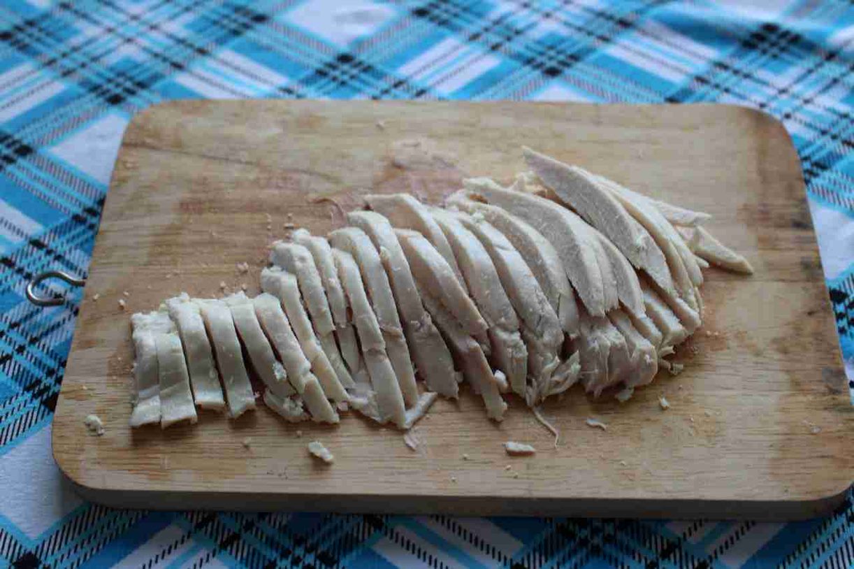 Подготавливаем продукты для салата с авокадо, манго и куриной грудкой. Нарезаем тонкой соломкой 200 граммов предварительно отваренной куриной грудки. Складываем в миску. 