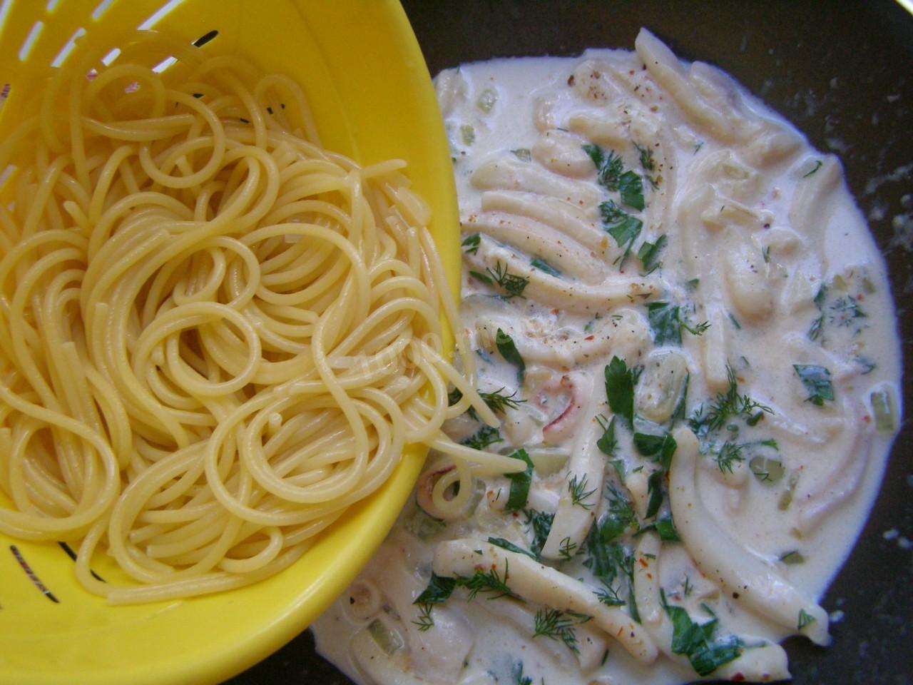 7.	Выложите спагетти в сковороду к кальмарам. Влейте сливки, добавьте помидоры, зелень. Все хорошо и аккуратно перемешайте. Накройте сковороду крышкой и тушите еще 5 минут. В конце посолите, поперчите по вкусу.