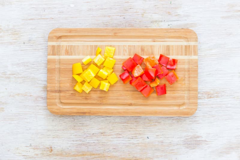 Огурцы для греческого салата вымойте и обсушите. Разрежьте вдоль пополам, вырежьте семена и нарежьте ломтиками толщиной 5-6 мм. Перец нарежьте квадратами со стороной 1.5 см.