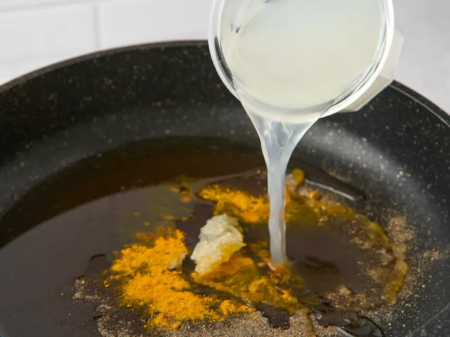 Поставьте сковороду с маслом на средний огонь, хорошо разогрейте. Положите в масло куркуму, черный перец и чеснок, влейте 0,5 стакана отвара от пасты. Прогрейте, помешивая, 30 секунд.