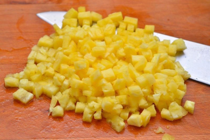 Нарежьте ананасы мелкими кусочками и слегка отожмите.
