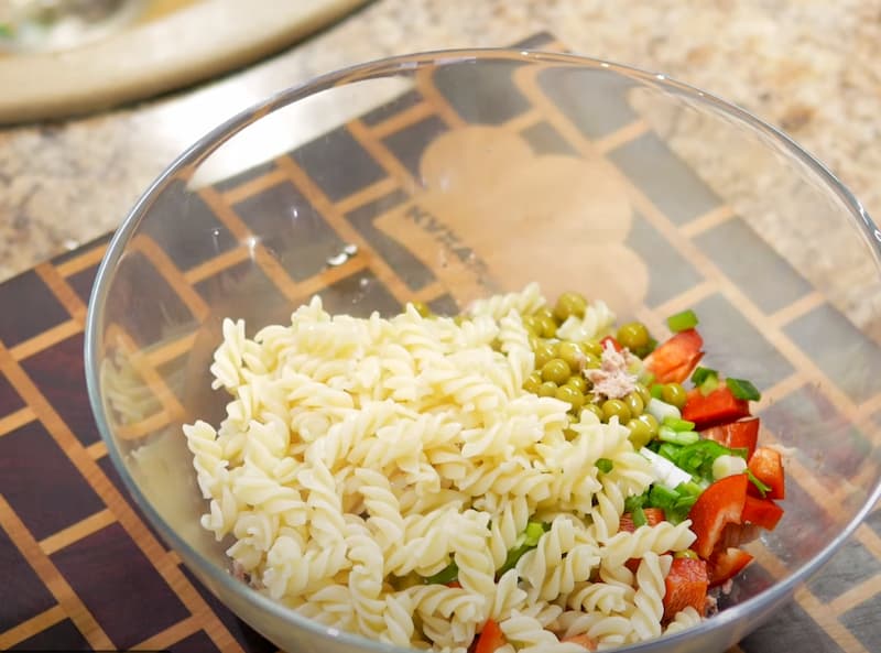 Добавляем в салат макароны, заправку, соль и перец. Хорошенько перемешиваем.