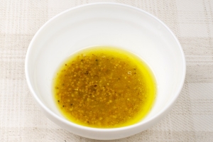 Готовим заправку для салата: смешиваем оливковое масло с уксусом и зернами горчицы.
