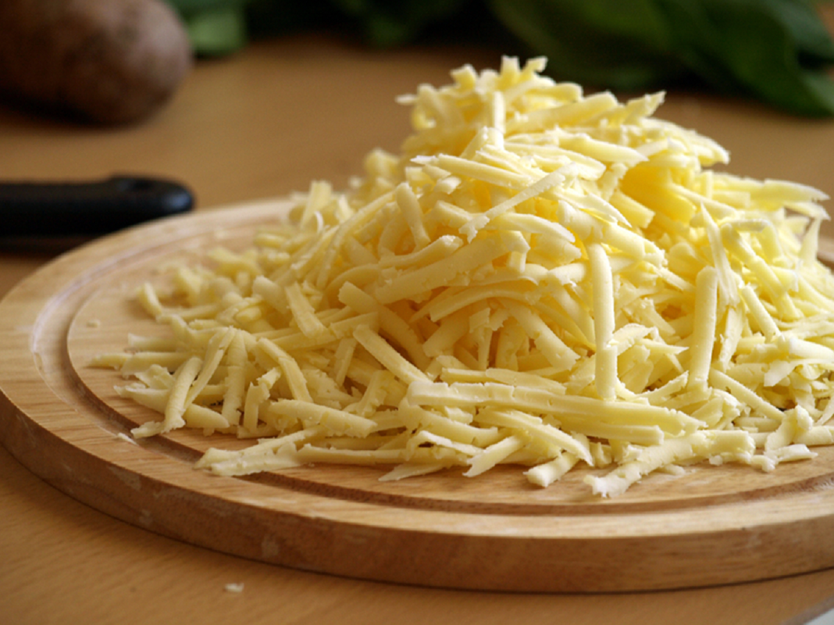 На крупной терке натрите вкусный твердый сыр, который будет хорошо плавиться в духовке. Добавьте к смеси из сливок и яиц. Перемешайте.