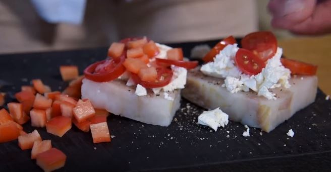 Нарезать томаты кружочками, сыр Фета разделить на небольшие кусочки и выложить с томатами на рыбу.