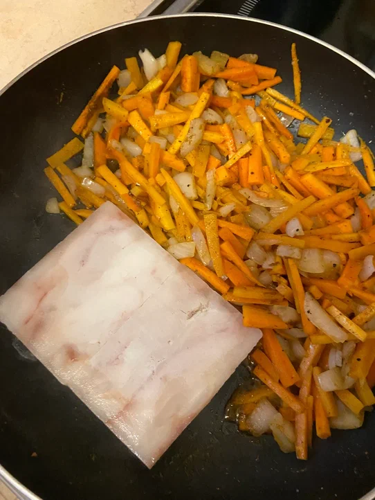 Овощи сдвинуть к краю сковородки, на освободившуюся часть налить еще немного масла, выложить рыбу (филе можно нарезать не небольшие куски или же положить целиком и разделить потом), немного обжарить.