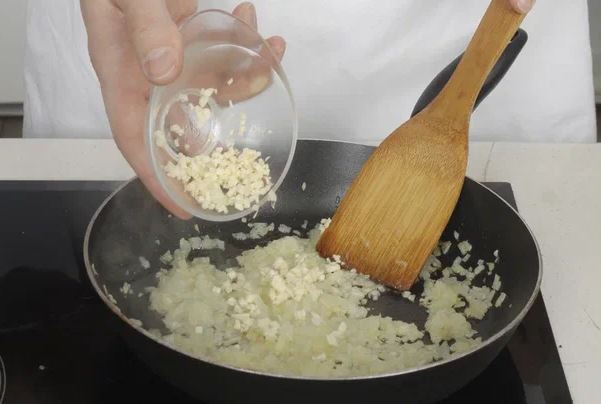 Лук и чеснок очистите и по отдельности очень мелко нарежьте. В глубокой сковороде с толстым дном на среднем огне разогрейте масло, положите лук, обжарьте до мягкости, 5 мин. Добавьте чеснок, обжаривайте еще 2 мин.