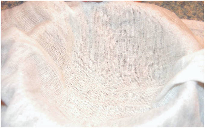 Сначала заморозить кефир (около 8–10 часов в морозилке). Далее подготовить глубокую миску, на которую нужно установить сито с 6–8 слоями марли, как показано на фото.