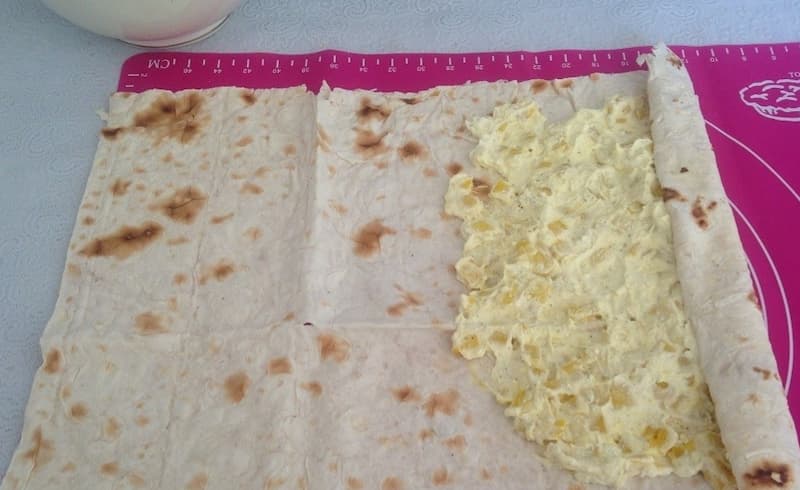 Смазать лист лаваша половиной готовой массы и свернуть рулет.  Повторить это со вторым листом лаваша. 