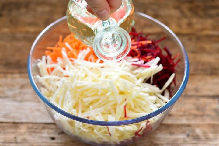 Соединить в салатнице капусту, морковь, свеклу, заправить оливковым маслом и перемешать.