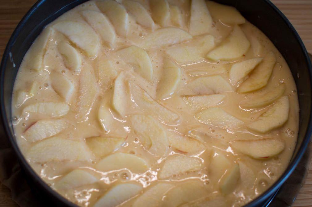 Яблоки хорошенько промойте. Разрежьте яблоки пополам, удалите сердцевинки. Нарежьте яблоки крупными кубиками. Добавьте яблоки в тесто. Перемешайте.