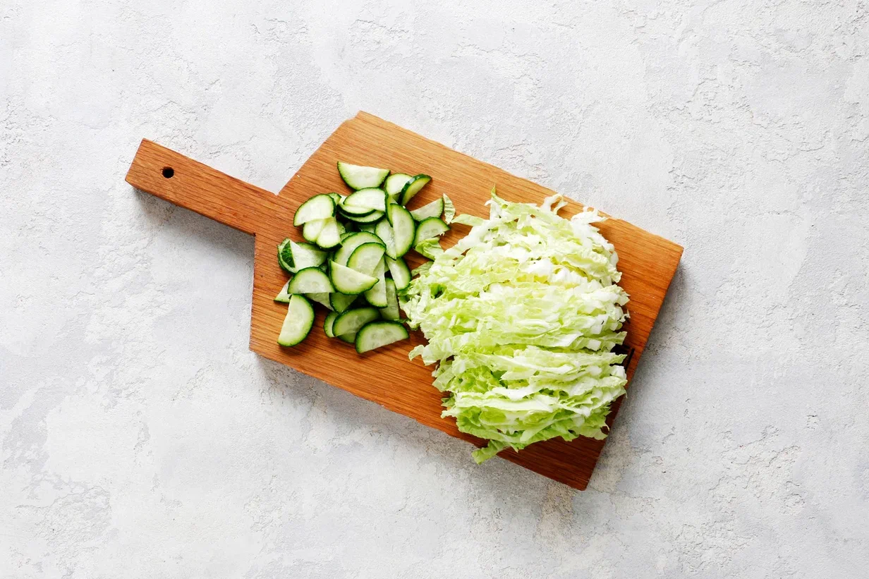 Пекинскую капусту почистите и нарежьте тонкой соломкой. Свежие огурцы вымойте. По желанию, плоды можно очистить от кожицы и крупных семян, если они крупные. Мякоть нарежьте небольшими ломтиками.