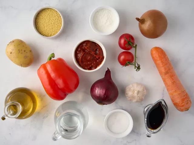 Помойте и почистите картофель, морковь, чеснок, красный и репчатый лук. Вымойте и обсушите сладкий перец, вырежьте из него сердцевину с семенами. Профильтруйте и вскипятите воду, остудите ее до теплого состояния. Подготовьте разделочную доску, сковороду в