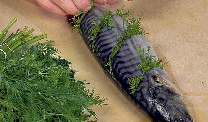 Скумбрию выпотрошить, тщательно промыть внутри и снаружи. Ножницами отрезать плавники. Сделать на коже с каждого бока по 4 глубоких диагональных надреза, вложить в них по 2–3 маленькие веточки укропа. Накрыть. Поставить в холодильник минимум на 20 мин.