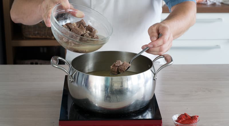 Бульон для харчо перелейте в кастрюлю и доведите до кипения. Рис тщательно промойте. Всыпьте в кипящий бульон и посолите. В бульон с рисом положите нарезанную говядину и варите на небольшом огне 10 минут. Добавьте томатную пасту и перемешайте.