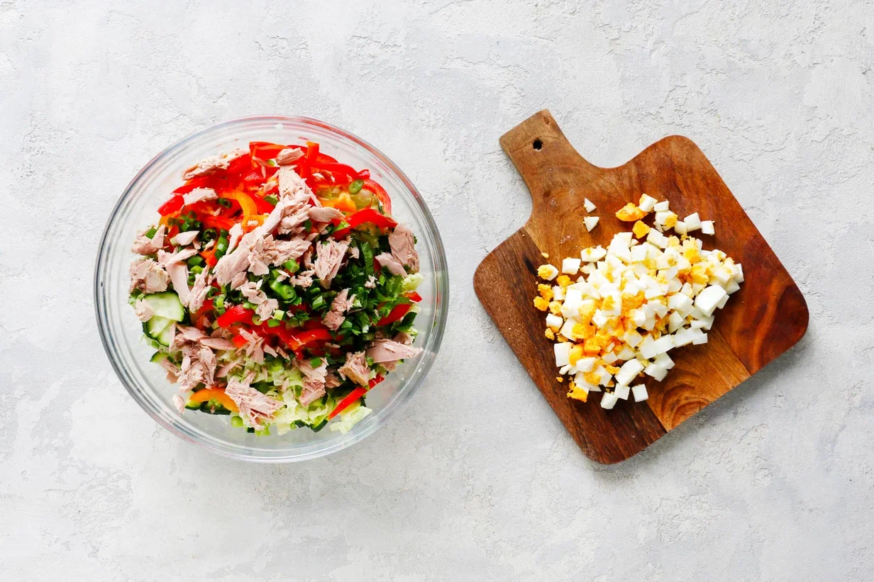 Яйца очистите и нарежьте мелкими кубиками. Соедините с пекинской капустой, огурцами, сладким перцем, луком, петрушкой и тунцом. Немного посолите и поперчите.