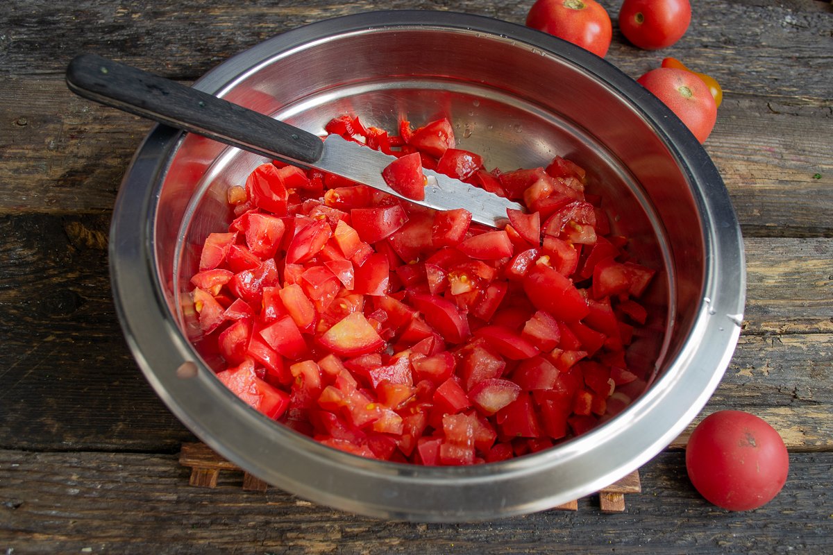 Нарезать помидор мелко и добавить в миску.
Посолить, поперчить, перемешать.