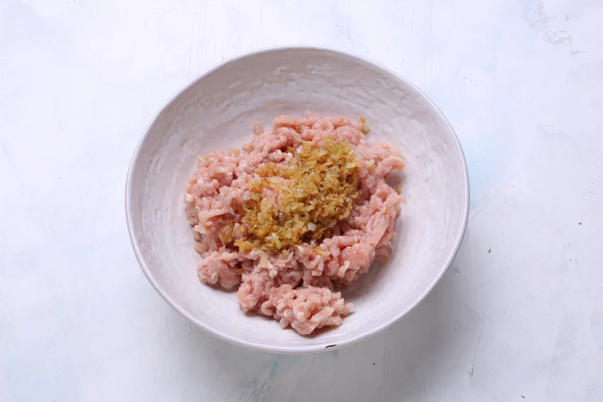 Куриную мякоть для «ежиков» пропустите через мясорубку. Лук очисите и порубите. Подрумяньте на сливочном масле и дайте остыть. Чеснок очистите, пропустите через пресс. Половину добавьте в куриный фарш вместе с луком.