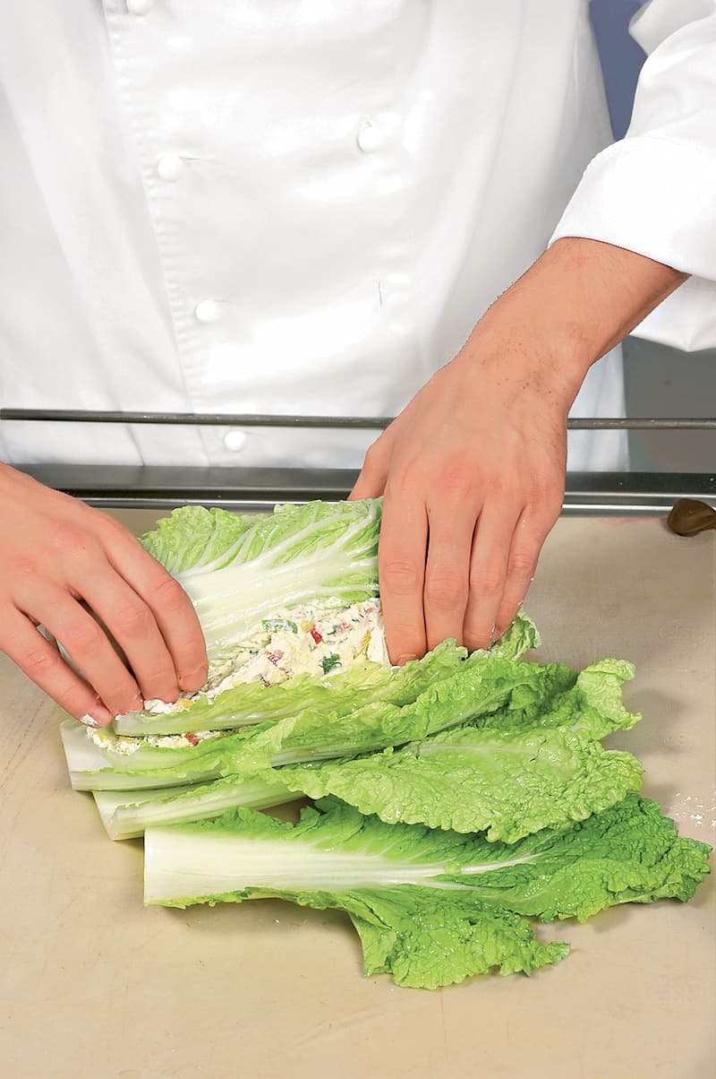 Разровнять поверхность и аккуратно свернуть листья в обратном порядке так, чтобы они вновь образовали кочан. Перевязать стеблями зеленого лука.