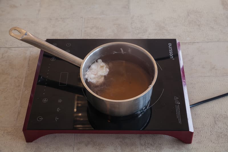 Вскипятите в ковшике воду, посолите и добавьте уксус. Разбейте в чашку яйцо, воду в ковшике закрутите воронкой и аккуратно вылейте яйцо. Варите 3 мин., затем аккуратно достаньте шумовкой и переложите на блюдце. Таким образом сварите все яйца.