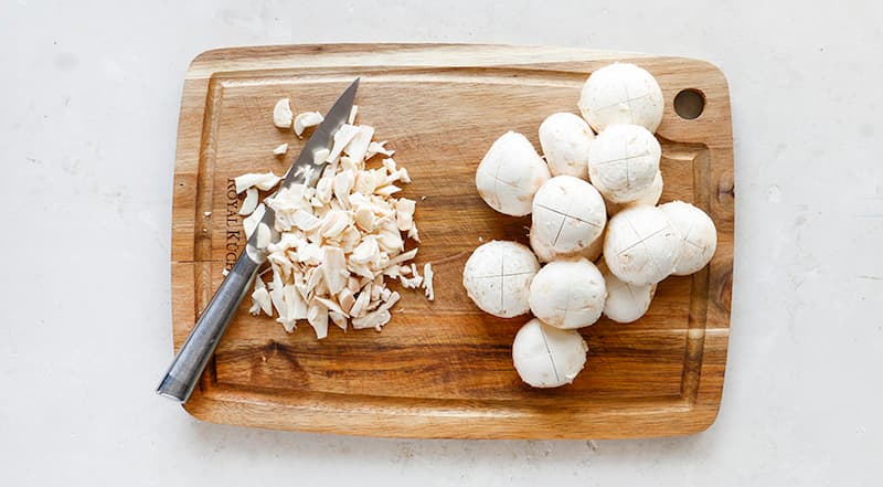 У грибов выломайте ножки и мелко нарежьте. Шляпки оставьте целыми, только на верхушке сделайте крестообразный надрез.