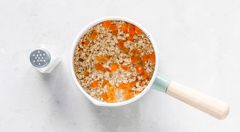 Накануне вечером нарежьте курагу небольшими кусочками. Замочите овсяную крупу вместе с курагой в нагретой до 38–40°С минеральной воде с солью. Если у вас есть мультиварка, то удобно это делать прямо в ней, ну или в обычной кастрюле на 8–12 ч.