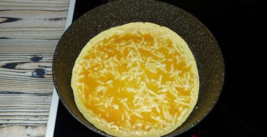 На разогретую сухую сковороду выложить лепёшку, немного подрумянить (1-2 минуты) и вылить яйца с сыром.