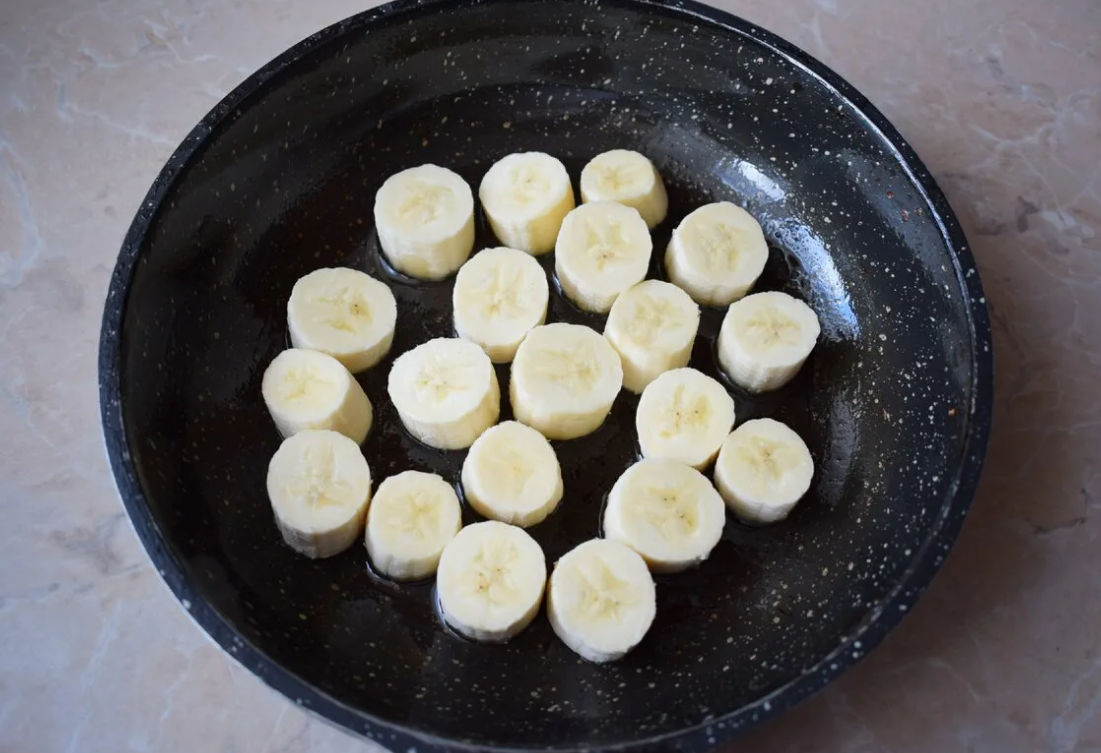 На сковородку налить масло, положить нарезанные средними кубиками бананы. Добавить немного воды и проварить бананы на среднем огне 2–3 минуты. Снять с огня, дать немного остыть и перемешать с медом.