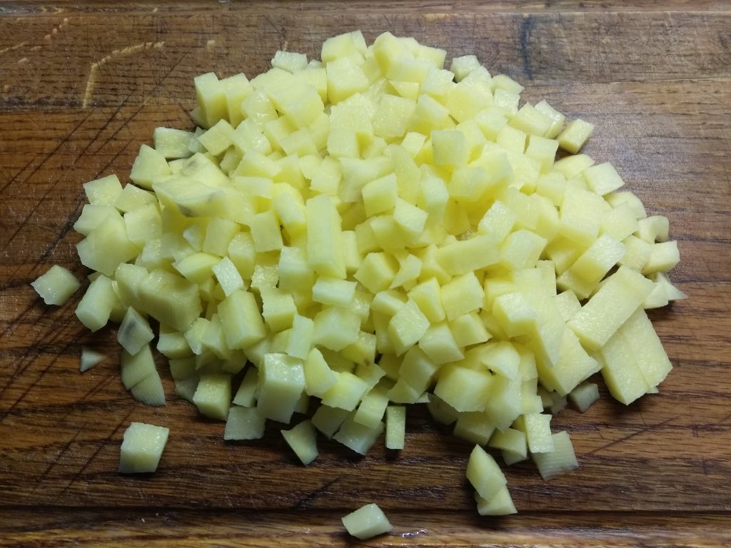 Нарезать картошку кубиками помельче и отправить к луку, добавив еще немного жидкости, чтобы они там потушились, когда жидкость почти выпарится и картошка разварится, но не до конца, добавить 2 столовые ложки соевого соуса и еще 3–5 минут пожарить. В конце