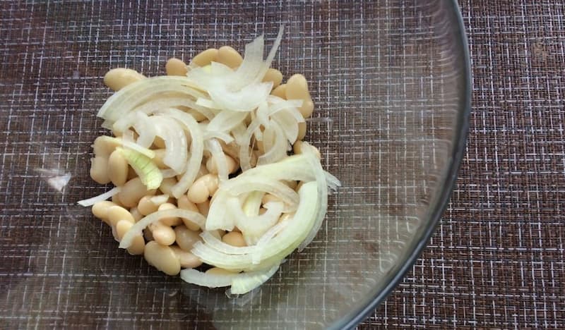Высыпать фасоль и лук в глубокую миску.