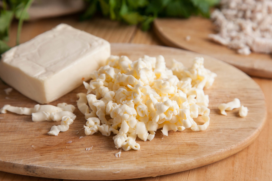 Плавленый сыр, чтобы он быстрее расплавился, лучше немного подморозить в морозилке и натереть на крупной терке. Плавленый сыр нужно использовать натуральный, хорошего качества. Натертый сыр кладем в кастрюлю с супом. Добавляем соль, черный молотый перец п