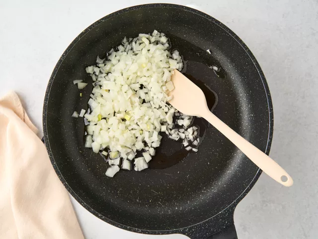 Разогрейте сковороду с маслом на среднем огне. Выложите в масло лук и чеснок, обжарьте их, помешивая, до мягкости.