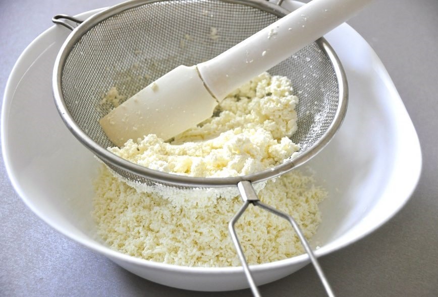 Для этого возьмите творог и только через сито протрите его. Переложите в миску, где вы будите замешивать тесто для вашей запеканки.  После этого в миску кладем щепотку соли, яйца, масло ванилин. Все тщательно перемешивать. 