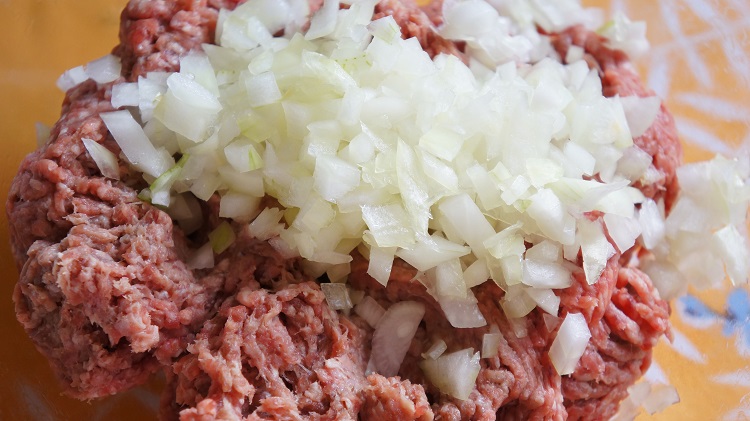 Лук измельчить в мясорубку. Фарш смешать с половиной лука.