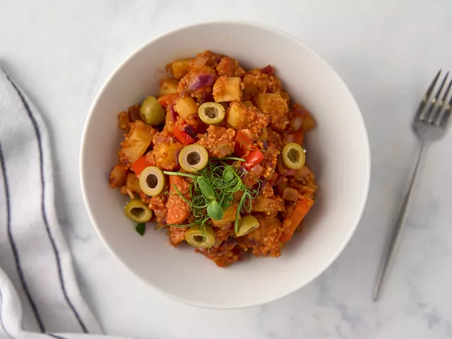 Украсьте овощи с кускусом оливками без косточек и микрозеленью.