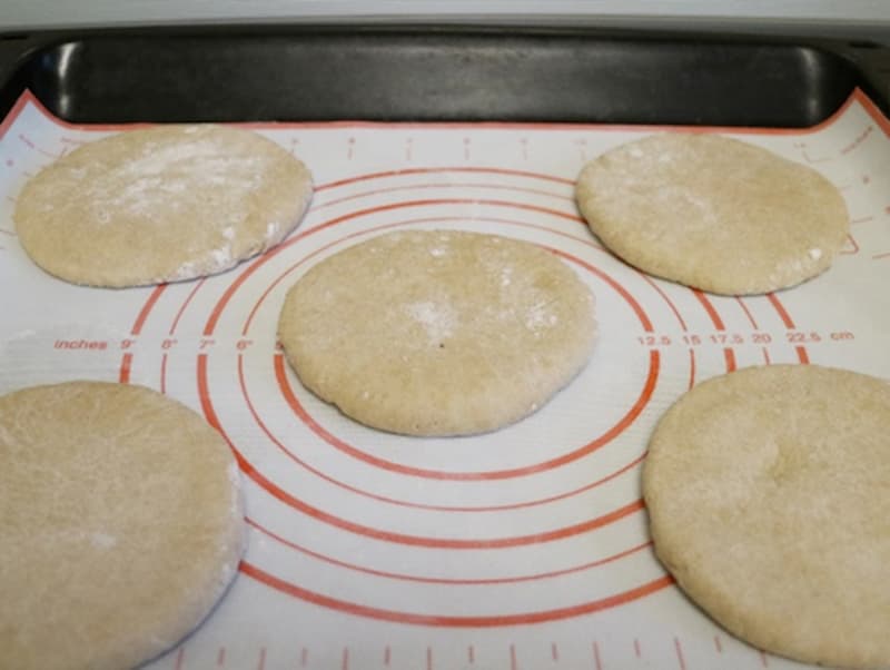 Расстоявшиеся шарики теста уплощаем вручную или при помощи скалки в ровный круг. Укладываем на пергамент или антипригарный коврик на некотором расстоянии. Равномерно распределяем творожную массу на круги и присыпаем сверху сыром.