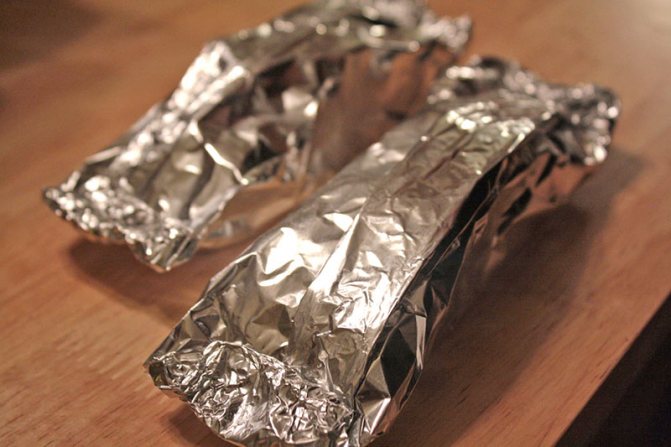 Уложите "солдатиком" начиненную селедку. Смажьте поверхность рыбы маслом. Заверните фольгу плотным швом свободным конвертиком и поставьте на 20 минут в нагретую до 180 градусов духовку. Через 20 минут откройте фольгу и снова поставьте рыбку в духовой шкаф