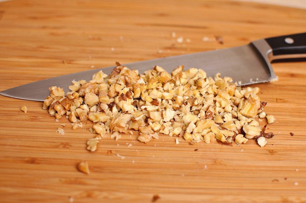 Очищенные от скорлупы ядра грецких орехов измельчите в ступке или мелко нарежьте ножом.