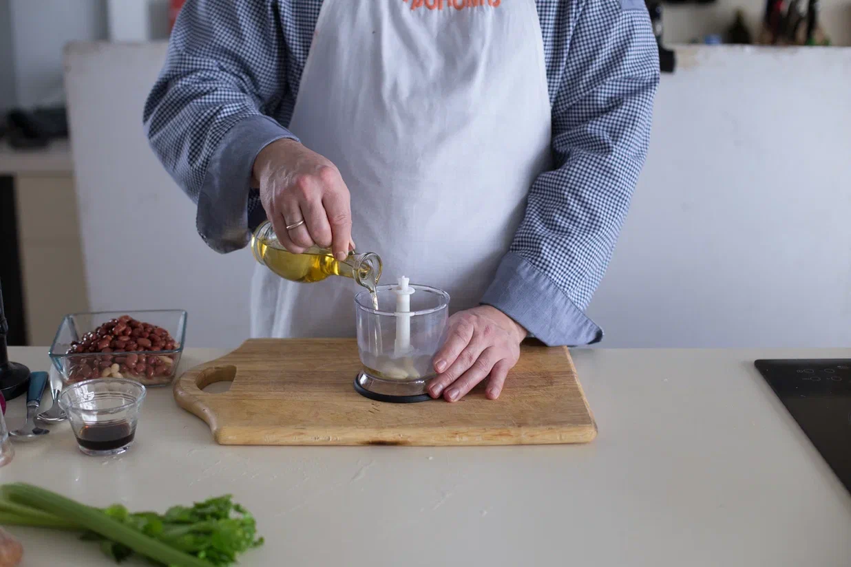 Приготовьте гренки для постного салата с фасолью. Разогрейте духовку до 180 °С. Раздавите и очистите чеснок, сложите в стакан блендера, посолите, влейте масло и взбейте до однородности.