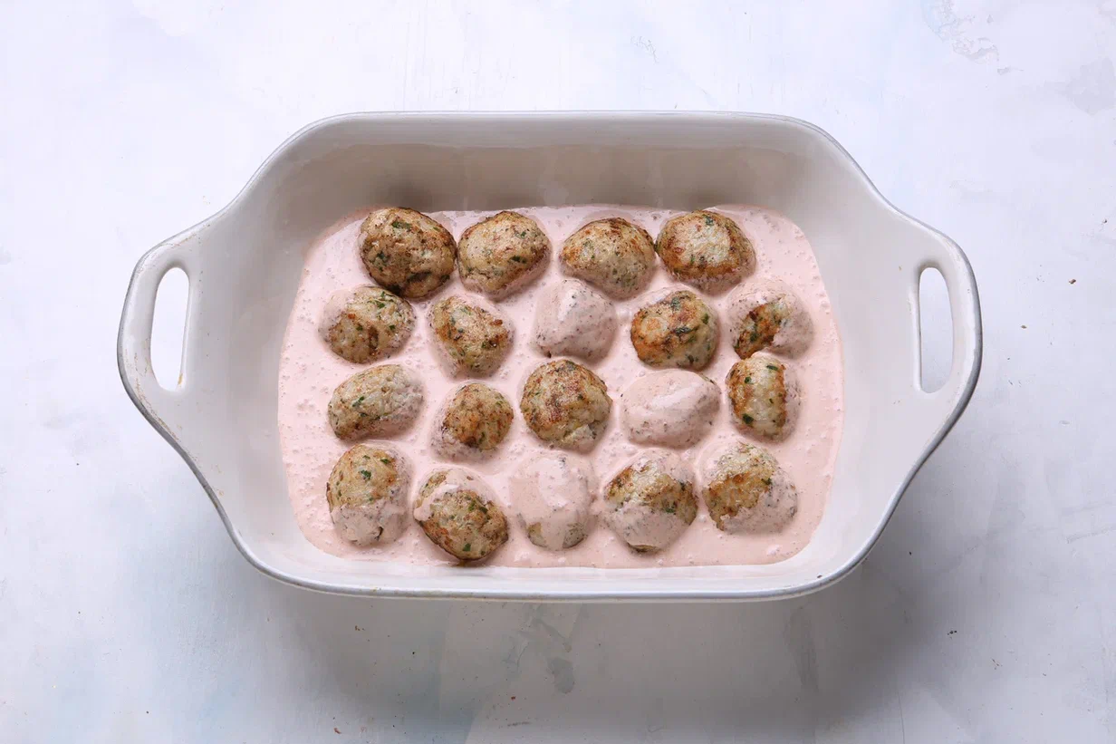 Сливки смешайте с томатной пастой. Приправьте паприкой, солью и перцем по вкусу. Куриные ежики залейте получившимся соусом. Запекайте 15 минут при 200°C. На стол подайте горячими.