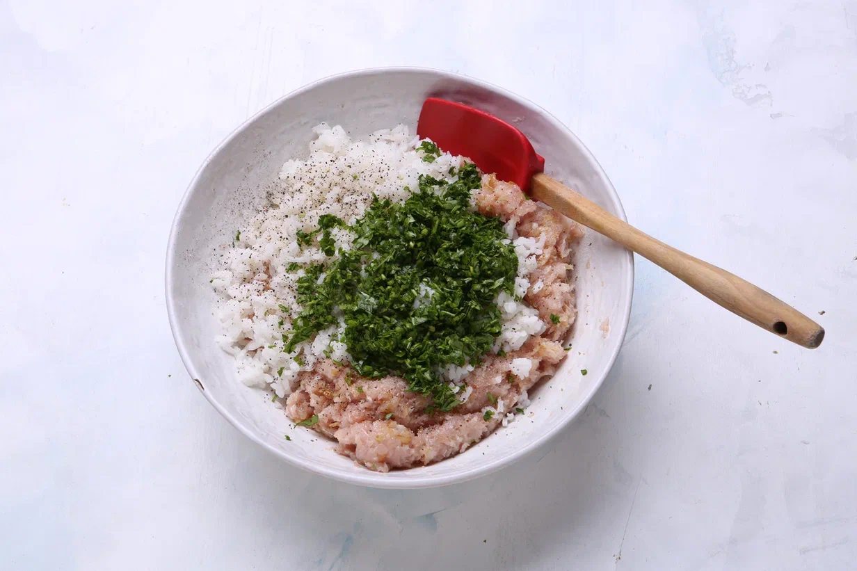 Петрушку вымойте, обсушите и оборвите с веточек листочки. Очень мелко нарежьте и добавьте в куриный фарш вместе с рисом. Оставьте на 10 минут при комнатной температуре. Сформируйте маленькие шарики.