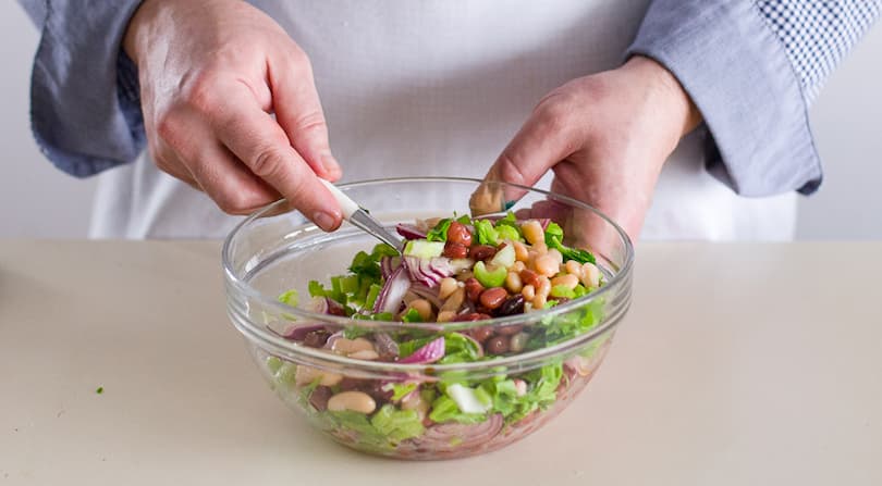 Откиньте фасоль на дуршлаг, при желании промойте питьевой водой. Смешайте фасоль с луком, сельдереем и остатками чесночного масла. Приправьте перцем.