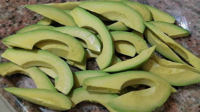 Два авокадо очищаем от кожицы и косточки и нарезаем тонкой соломкой. Отправляем к курице с луком. 