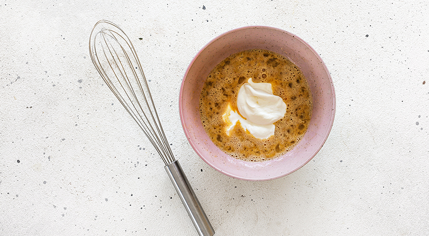 Приготовьте тесто для творожных пп-кексов. Для этого яйца комнатной температуры разбейте в миску и добавьте к ним заменитель сахара. Взбейте венчиком. Добавьте йогурт. Снова взбейте.