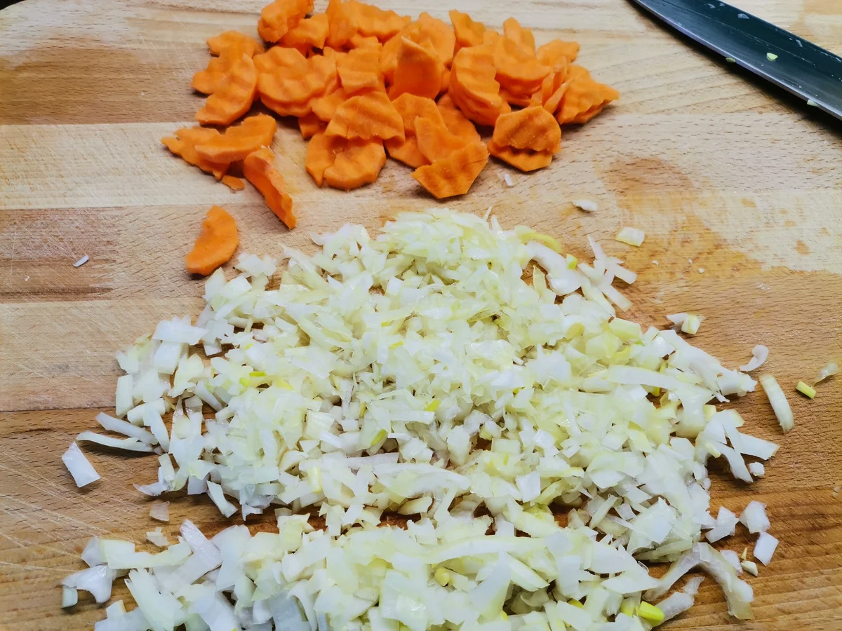 Очистите лук и морковь, лук нарежьте кубиками, морковь – полукольцами. Обжарьте лук с морковью до мягкости на сковороде, затем добавьте томатную пасту и жарьте еще 5 мин., постоянно помешивая. Переложите овощи в горшочки.