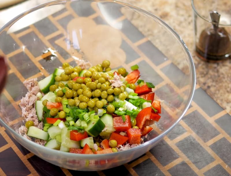 Огурец, болгарский перец и зеленый лук нарезаем кубиком и отправляем в салатницу вместе с зеленым горошком и тунцом. 