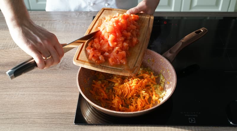 В сковороде нагрейте масло и слегка подрумяньте на среднем огне лук. Добавьте морковь и продолжайте жарить еще 5-7 минут. Положите помидоры и перемешайте. Тушите на слабом огне 7 минут.
